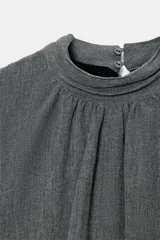 Vestido corto de color gris, con cuello subido, manga corta y diseño de cuerpo holgado con bajo tipo globo. Presenta cierre en la espalda con botones y cremallera oculta.