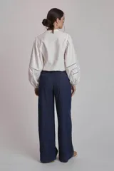 Camisa blanca de mangas largas abullonadas con detalles de calado en los puños y cuello mao.