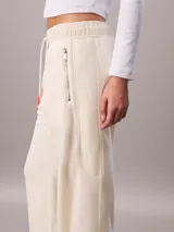 Jogger de tejido polar color blanco de Calvin Klein, con cintura elástica con cordón ajustable, bolsillos laterales con cremallera y puños elásticos en los tobillos.
