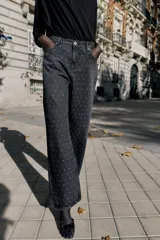 Jeans de tiro alto, corte recto y largo, color negro lavado, con abalorios brillantes distribuidos por toda la prenda.