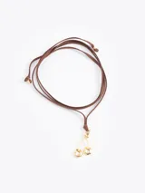 Choker de cordón largo de cuero sintético con dije metálico en forma de cerezas doradas.
