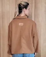 Chaqueta de textura bouclé en color bordó, con corte oversize, cuello camisero, cierre frontal y bolsillos laterales.