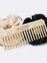 Kit de accesorios para el cabello que incluye un neceser transparente con borde blanco, dos scrunchies (uno negro con perlas y uno beige), dos clips livianos, una pinza dorada, un peine protector para desenredar y un peine para abrir ondas y rulos.