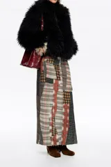 Chaqueta de pelo sintético negro con textura de pelo largo, cierre frontal con cremallera y cuello alto. Diseño de corte corto y envolvente.