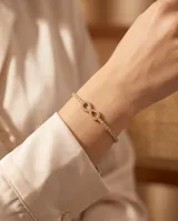 Pulsera de acero con baño de oro, diseño de infinito adornado con circonias y cadena tipo tenis.