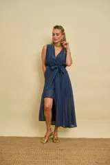 Vestido cruzado de organza color marrón, con escote en V, sin mangas y lazo para ajustar en la cintura. Presenta una falda con diseño asimétrico, más corta adelante y larga atrás.