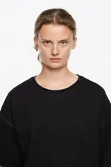 Camiseta de manga corta, corte recto y escote caja, color blanco crudo. Presenta pespuntes a contraste en color azul oscuro en las sisas y los bordes de las mangas.