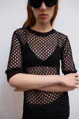 Jersey ajustado de color negro con diseño de punto calado, cuello redondo y mangas cortas.