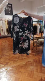 Vestido midi de manga larga con estampado floral sobre fondo oscuro, cuello redondo con abertura y diseño fluido.