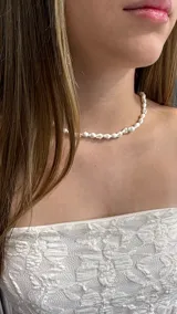 Gargantilla tipo choker compuesta por pequeños caracoles naturales de color blanco, dispuestos de forma continua alrededor del cuello.