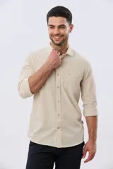 Camisa de lino de manga larga en color beige, con cuello camisero, cierre frontal de botones y un bolsillo ojal en el pecho.
