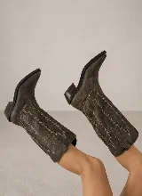 Bota de estilo texano confeccionada en cuero genuino, con caña alta y diseño de costuras decorativas en contraste. Presenta punta fina y taco cuadrado de madera.