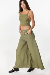 Pantalón de lino verde militar, de tiro alto y corte amplio con botamanga ancha. Cuenta con bolsillos delanteros aplicados y cierre frontal con botón y bragueta.