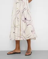 Vestido midi color crudo con estampado de flores abstractas en tonos morados y oliva, corte evasé, escote en V y cuello halter anudado en la espalda.