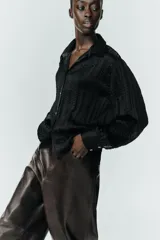 Camisa de manga larga con cuello solapa, confeccionada en tejido satinado con textura efecto arrugado y cierre frontal con botones.