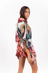 Vestido camisero oversize de tela calada con estampado abstracto multicolor, cuello camisero, mangas anchas y lazo ajustable en la cintura confeccionado en la misma tela.