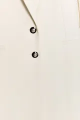 Blazer larga negra con cuello solapa, manga larga y bolsillos de vivo en el delantero. Cierre frontal con dos botones plateados.