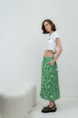 Falda midi de lino 100%, color verde con estampado de flores grandes en tonos de verde más claro y amarillo. Presenta pliegues en la cintura y corte amplio.