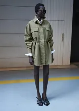 Parka verde militar de algodón, de diseño oversize con cuello camisero, manga larga, bolsillos con solapa en el pecho, bolsillos laterales y cordón ajustable en la cintura.