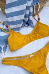 Conjunto de bikini color amarillo mostaza, con corpiño triangular con detalle de cuentas en los breteles y bombacha semivedetina.