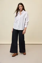 Camisa celeste de corte oversize, con mangas largas, cuello camisero y cierre frontal de botones.