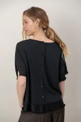 Remera negra de algodón con cuello redondo, mangas cortas y zócalo de satén desflecado en el ruedo y las mangas.