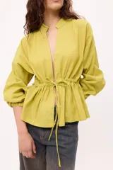 Chaqueta color verde claro con cuello mao, mangas largas abullonadas con puños elásticos y lazo ajustable en la cintura.