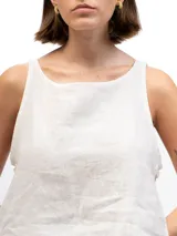 Musculosa blanca de lino con cuello redondo y laterales abiertos unidos por tres tiras cosidas.