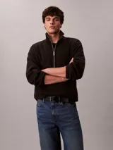 Buzo polar Calvin Klein de textura suave, con cuello alto y cierre de media cremallera frontal. Presenta un diseño de manga larga con corte regular y logo de la marca sutilmente bordado en el pecho.