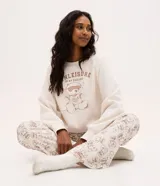 Buzo de pijama color crema, con cuello redondo y mangas largas. Presenta una estampa frontal de un osito con antifaz y la frase Athleisure in my dreams.