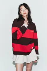 Polo de manga larga con cuello solapa y cierre frontal de botones. Diseño a rayas horizontales anchas en color negro y rojo. Presenta texto bordado en el pecho y parches decorativos en la parte inferior delantera.