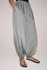Pantalón de tiro medio con pierna ancha y cintura elástica, confeccionado en mezcla de viscosa con diseño de rayas verticales en tonos mostaza y marrón.