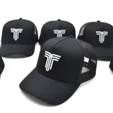 Gorra tipo trucker color negro, con panel frontal rígido y parte trasera de malla. Presenta un logo bordado en relieve de color blanco en el frente.