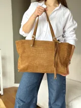 Cartera tote de cuero gamuzado color marrón con grabado efecto cocodrilo, asas de hombro regulables con hebillas metálicas y tiras colgantes decorativas con flecos.