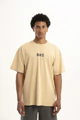 Remera color beige de corte holgado con estampado pequeño de palmera y la letra S en el centro del pecho.