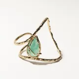 Brazalete rígido dorado con una piedra verde en forma de lágrima.