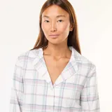 Conjunto de pijama de dos piezas, compuesto por una camisa de manga larga con cuello y botones, y un pantalón largo con cintura elástica. Diseño a cuadros en tonos pastel.