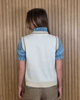 Chaleco tejido de punto 100% algodón, color crudo con detalles en tono tostado en el cuello redondo, sisas y dobladillo inferior.