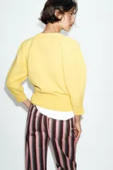 Jersey de punto color amarillo claro, con cuello redondo y mangas abullonadas.
