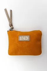 Billetera de gamuza color mostaza, con cierre superior y tirador de cuero sintético metalizado. Incluye placa metálica con grabado frontal.