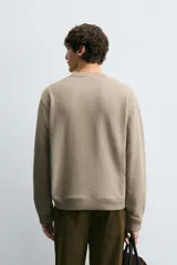 Sudadera de cuello redondo con ajuste regular, confeccionada en tejido de mezcla de algodón con interior de rizo y acabados en rib en cuello, puños y ruedo.