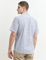 Camisa de manga corta a rayas verticales celestes y blancas, con cuello abotonado y corte clásico.