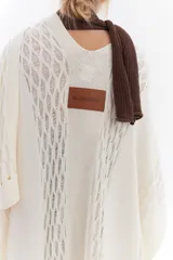 Ruana de punto color beige con detalles texturizados y tramados abiertos, ligera y versátil.