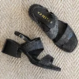 Sandalia de cuero negro con textura, estilo dos tiras anchas y taco cuadrado de madera de 5 cm de altura. Posee una tira fina ajustable en el tobillo.