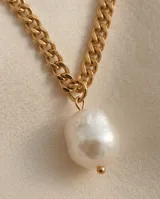 Collar doble de acero dorado, compuesto por una cadena de eslabones rectangulares y una cadena fina con dije de perla de río natural.
