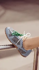 Zapatillas urbanas de cuero celeste y mesh gris, con suela de goma y doble juego de cordones intercambiables en color verde y blanco.