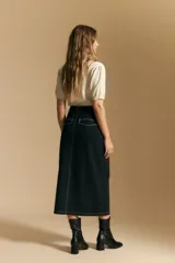 Falda midi negra de denim con costuras blancas contrastantes y tajo frontal.