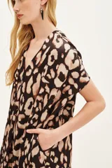 Vestido midi de corte holgado con estampado animal print, cuello en V y mangas cortas. Cuenta con bolsillos laterales.