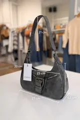 Cartera de hombro de tamaño compacto con acabado texturizado efecto cuero desgastado. Presenta un diseño con cierre superior, bolsillos frontales con cierre y una solapa central decorativa con hebilla metálica. Incluye asa fija para llevar al hombro.