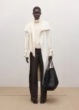 Blusa de seda color crema con cuello alto y detalle de pañuelo integrado en el escote. Presenta un diseño fluido y elegante de manga larga.